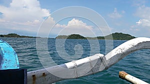 Traditional Indonesian boat sails between tropical islands on a sunny day,View from beach on traditional Indonesian