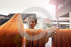 Traditional Isan Thai silk weaving. old woman hand weaving silk Akkanee in traditional way at manual loom. Phu fabric dyeing