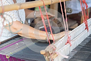 Traditional Isan Thai silk weaving. Older women hand weaving silk in traditional way at manual loom