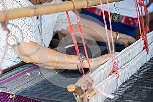 Traditional Isan Thsilk weaving. old woman hand weaving silk in traditional way at manual loom