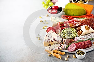 Traditional italian antipasto, cutting board with salami, cold smoked meat, prosciutto, ham, cheeses, olives, capers on