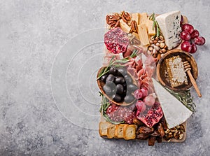 Traditional italian antipasto plate. Assorted cheeses on wooden cutting board. Brie cheese, cheddar slices, gogonzola, walnuts gra