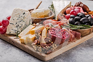 Traditional italian antipasto plate. Assorted cheeses on wooden cutting board. Brie cheese, cheddar slices, gogonzola, walnuts