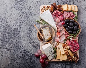 Traditional italian antipasto plate. Assorted cheeses on wooden cutting board. Brie cheese, cheddar slices, gogonzola, walnuts