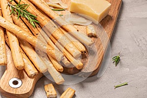 Traditional italian breadsticks grissini with rosemary, parmesan cheese, olive oil, garlic and salt on a gray background