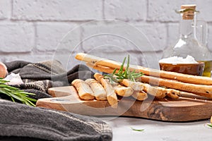 Traditional italian breadsticks grissini with rosemary, parmesan cheese, olive oil, garlic and salt on a gray background