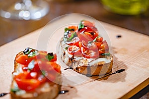 Traditional Italian bruschetta with cherry tomatoes, cheese, basil and balsamic vinegar on wooden board. photo