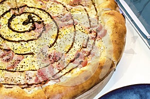 Traditional italian carbonara pizza with bacon, mozzarella, parmesan in restaurant close-up