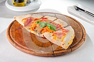 Traditional Italian closed pizza Calzone on the wooden board on the served restaurant table. Selective focus.