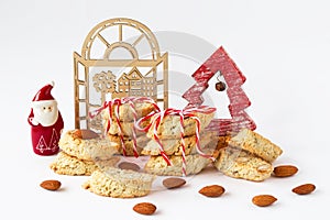 Traditional Italian cookies - cantucci or biscotti with almond and red-white Christmas decorations on white background