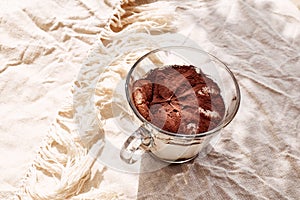 Traditional Italian dessert Tiramisu in a glass cup on a table with linen tablecloth. National cuisine recipe.