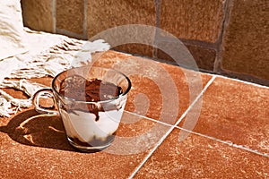 Traditional Italian dessert Tiramisu in a glass cup on a tile table. National cuisine recipe.