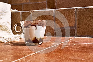Traditional Italian dessert Tiramisu in a glass cup on a tile table. National cuisine recipe.