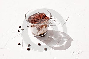 Traditional Italian dessert Tiramisu in a glass cup on white background. National cuisine recipe.
