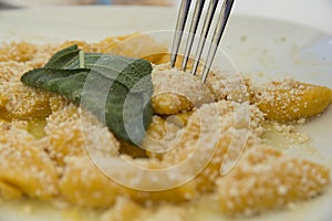 A traditional Italian dish: Pumpkin Gnocchi with Parmesan cheese and a decorative sage leaf