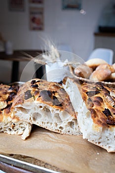 Traditional Italian focaccia bread on a tray surrounded by other bread. Photo from a small artisan bakery.