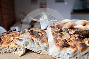 Traditional Italian focaccia bread on a tray surrounded by other bread. Photo from a small artisan bakery.