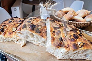 Traditional Italian focaccia bread on a tray surrounded by other bread. Photo from a small artisan bakery.