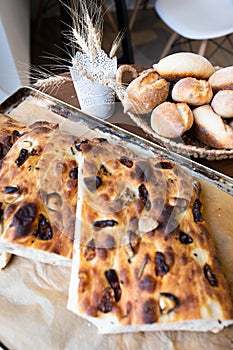 Traditional Italian focaccia bread on a tray surrounded by other bread. Photo from a small artisan bakery.