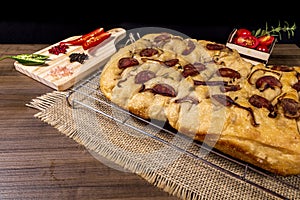 Traditional Italian Focaccia with pepperoni, cherry tomatoes, black olives, rosemary ando onion - homemade flat bread focaccia photo