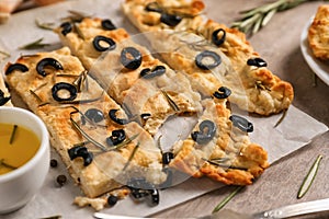 Traditional Italian Focaccia with rosemary, olives and oil on table