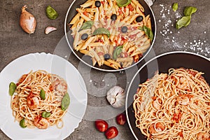 Traditional Italian food. Pasta with tomato sauce, basil, parmesan, olives. Food in a pan and on a plate. View from above