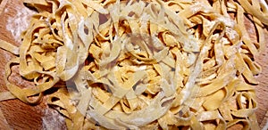 Traditional Italian homemade noodles Tagliatelle on wooden background - closeup on fresh pasta