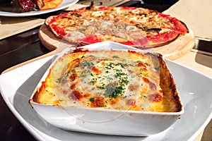 Traditional Italian Lasagna made with Minced Beef Bolognese Sauce topped with Basil Leaves served on a White Plate