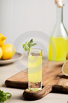 Traditional Italian liqueur Limoncello. Glass bottle with homemade Limoncello liqueur, plate with lemons and celery