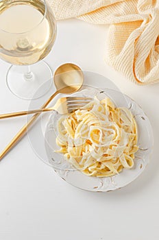 Traditional Italian pasta - Fetuccini Alfredo on a white table with golden appliances