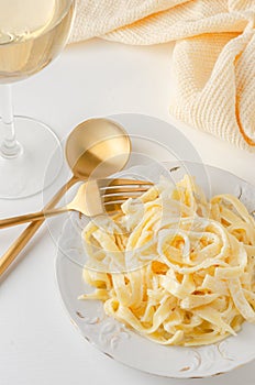 Traditional Italian pasta - Fetuccini Alfredo on a white table with golden appliances