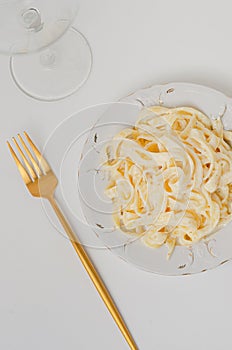 Traditional Italian pasta - Fetuccini Alfredo on a white table with golden appliances