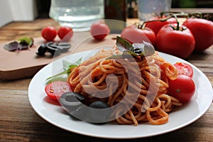 Traditional Italian pasta and ingredients on the white plate on rustic wooden table background. Long spaghetti with tomato sauce,