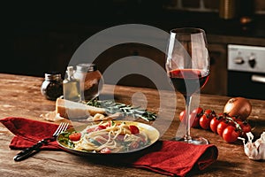 Traditional Italian pasta with tomatoes and arugula in plate and glass of