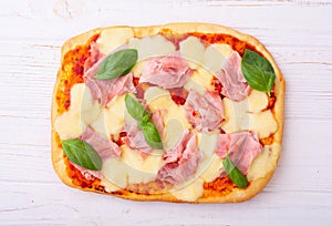 Traditional italian pizza with ham mozzarella and basil