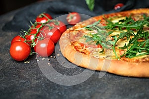 Traditional Italian pizza with ham, mozzarella, basil, arugula and tomatoes