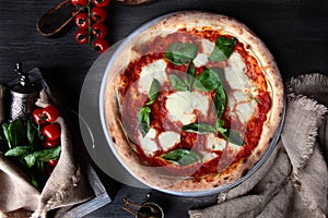 Traditional Italian pizza Margarita. Basil leaves and tomato sauce. Metal plate for serving food. Vertical photo