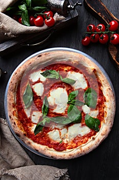 Traditional Italian pizza Margarita. Basil leaves and tomato sauce. Metal plate for serving food. Vertical photo