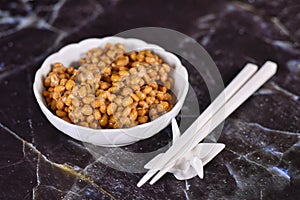 Traditional Japanese food called `Natto` made from fermented soybeans in bowl with chopsticks