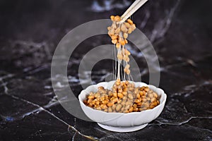 Traditional Japanese food `Natto` made from fermented soybeans drawing sticky strings on chopsticks