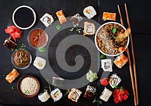 Traditional Japanese food - sushi, rolls, rice with shrimp and sauce on a dark background.