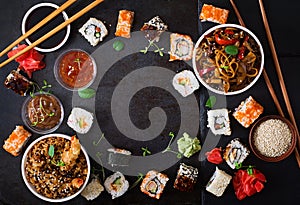 Traditional Japanese food - sushi, rolls, rice with shrimp and udon noodles with chicken and mushrooms on a dark background.