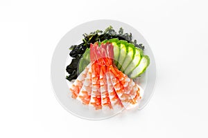 Traditional japanese sashimi with prawn, seaweed and cucumber on a white background top view
