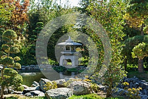 Traditional Japanese stone lamp, Snow Lantern by Yukimi Toro near shore of pond in Japanese garden photo