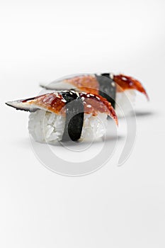Traditional japanese sushi nigiri with smoked eel on a white background, vertical shot. Unagi smoked eel top view