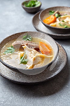 Traditional Jewish food dumplingd kreplach soup in gray bowl.