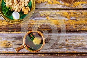 Traditional Jewish matzo ball soup and seder plate on wooden table