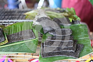 A traditional Karen food dessert made with glutinous rice flour, pounded with black sesame seeds and grilled over a fire