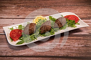 Traditional kebbe and pita bread on big round plate in lebanese restaurant