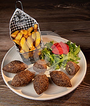 Traditional kebbe and pita bread on big round plate in lebanese restaurant